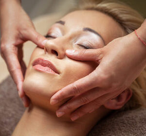 Femme recevant un massage facial relaxant.
